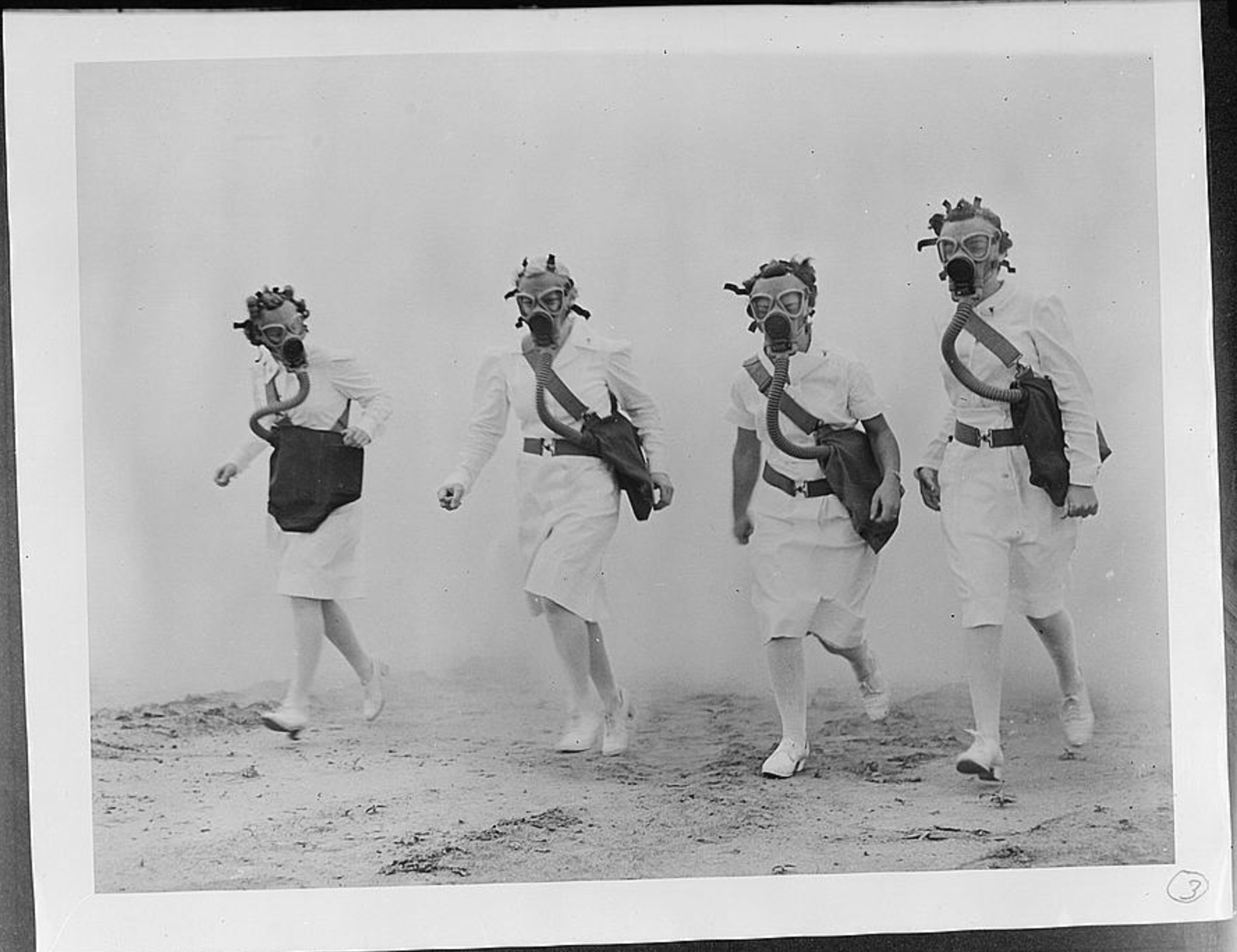 U.S. Army nurses advancing through a cloud of smoke in a gas mask drill at Scott Field, Illinois, c. 1942